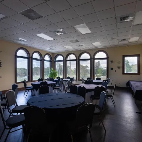 A spacious dining room inside with skirted tables and chairs.