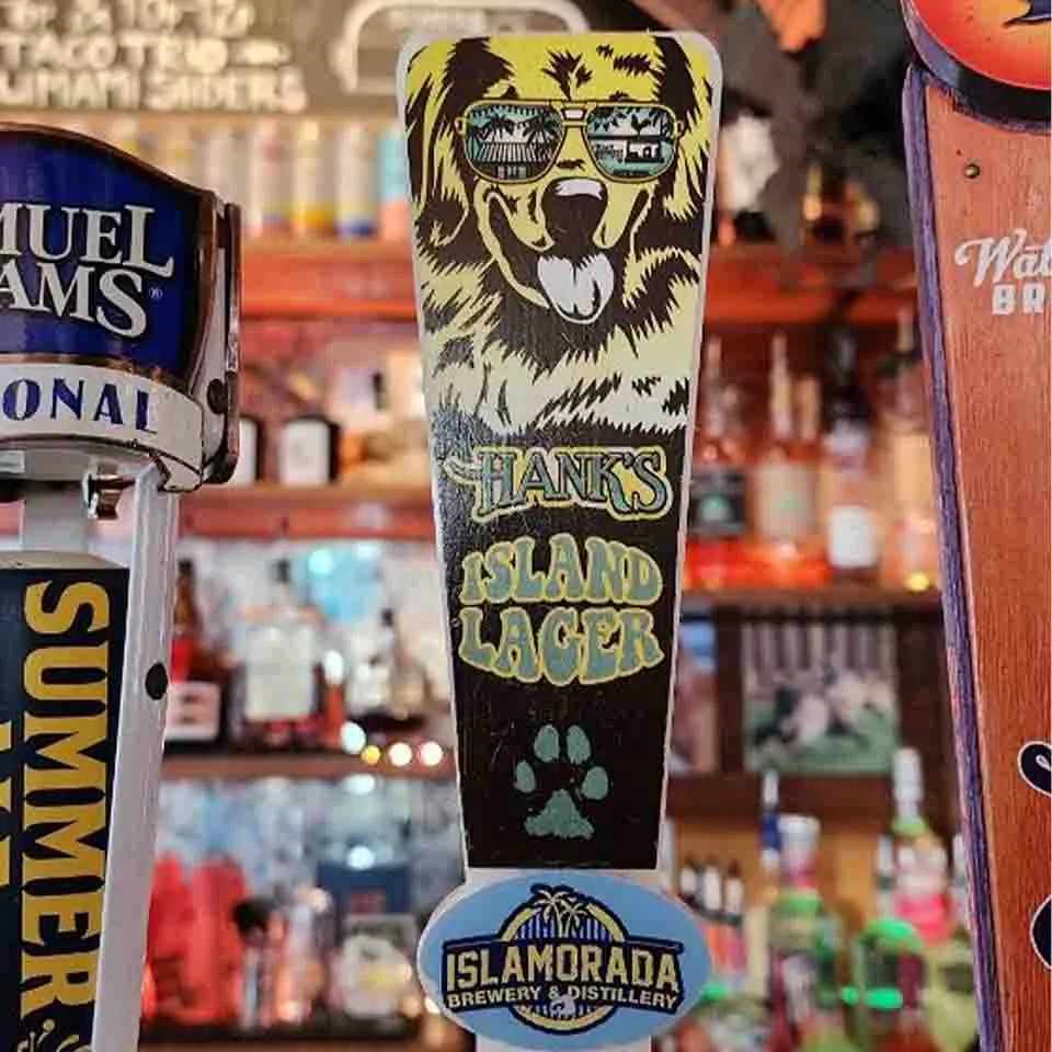 Beer tap handle featuring a dog in sunglasses, labeled "Hank's Island Lager," brings a touch of Key West bar flair to the scene.
