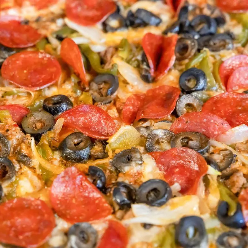 Pizza, featuring black olives, pepperoni, bell peppers and sausage, close-up.