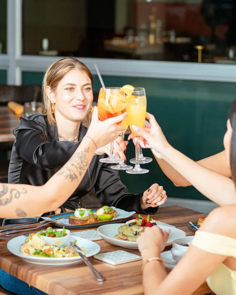 A group of people sitting at a table with food and drinks.