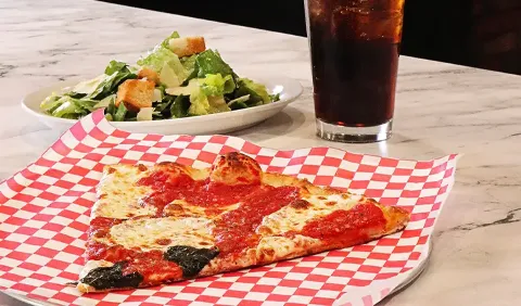 close up of a pizza slice and soda
