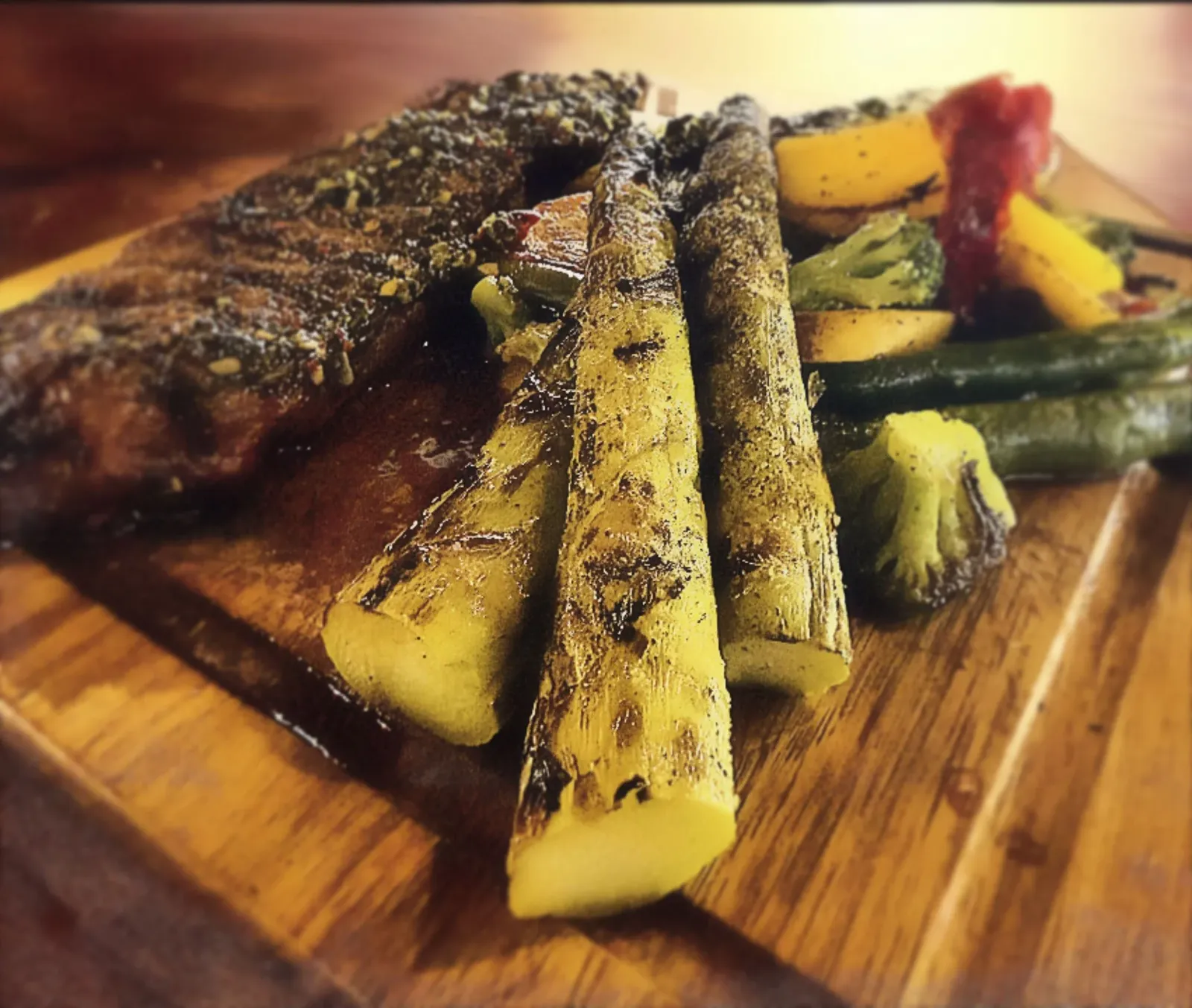 Grilled steak, jumbo asparagus and mixed vegetables on a wooden platter.