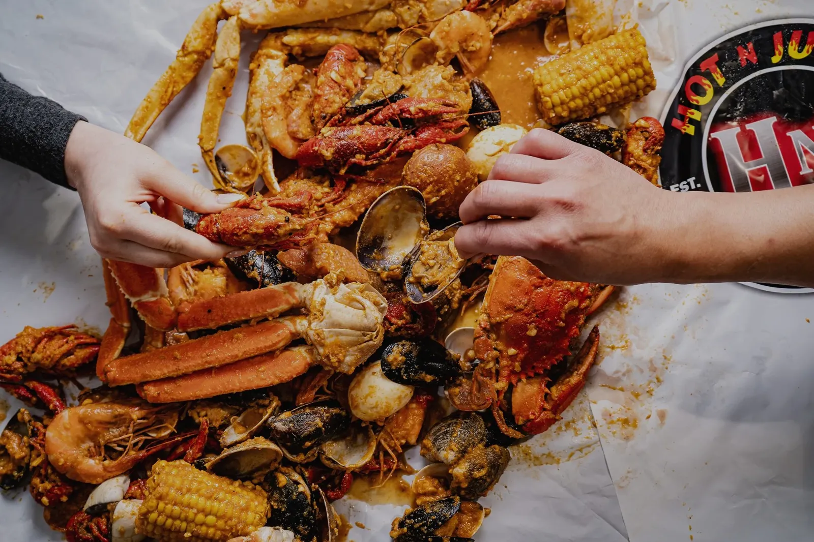 Seafood boil with crab legs, shrimp, clams, mussels, corn on the cob, and potatoes, served on parchment paper.