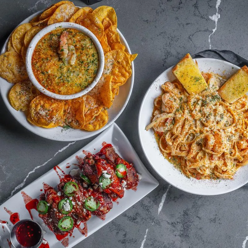 Two appetizers served on the table with a plate of pasta, top view.