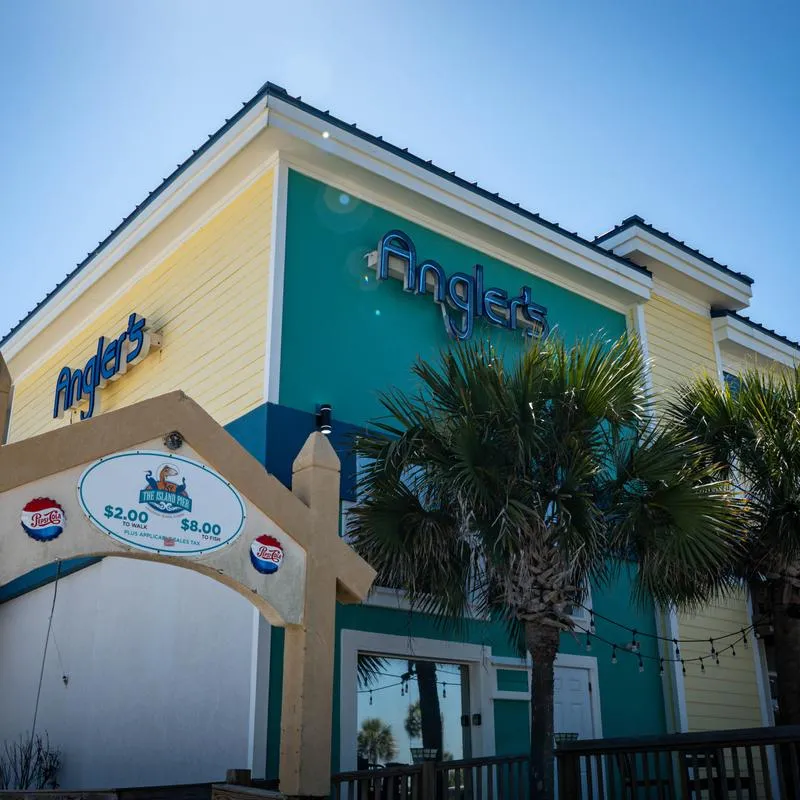 Restaurant exterior with entrance, signage and palm trees.