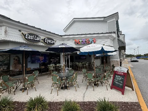 The covered patio at Mixers Bar & Grill in Palm Harbor — umbrellas, bistro seating, and the neon Mixers sign