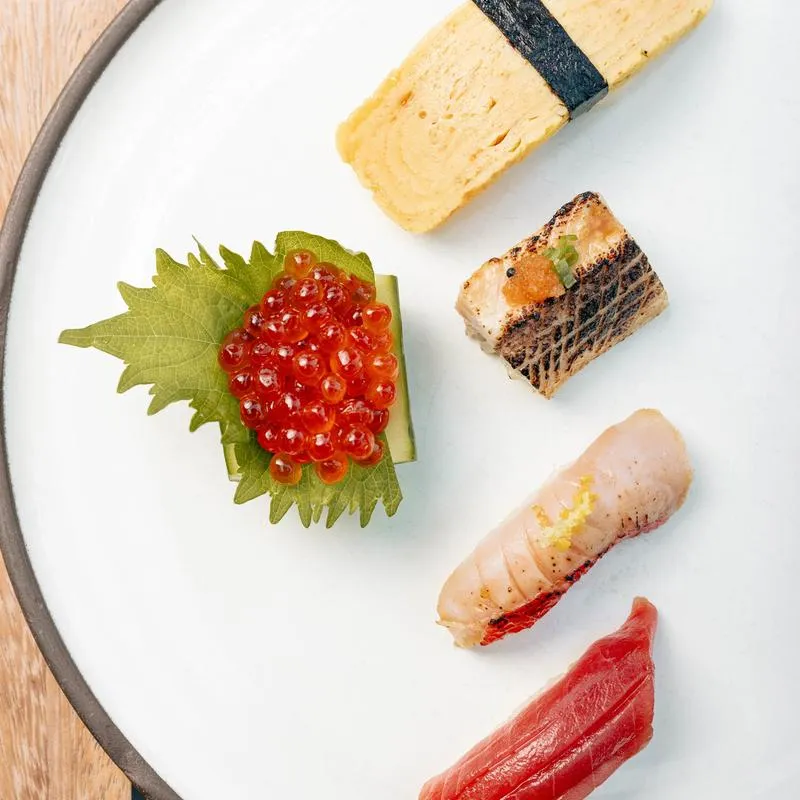 Colorful nigiri arranged on a white plate.