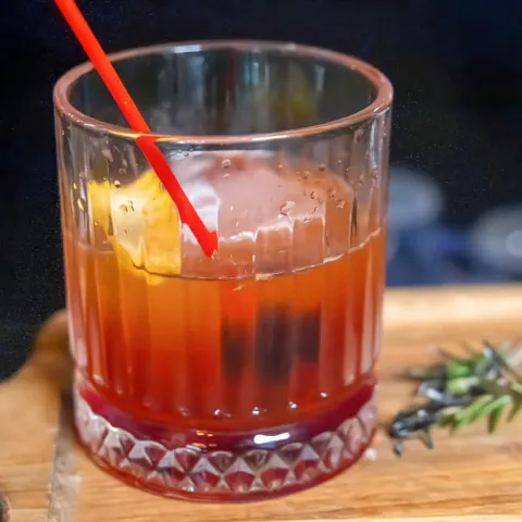 Old Fashioned cocktail garnished with a cherry and a citrus peel.