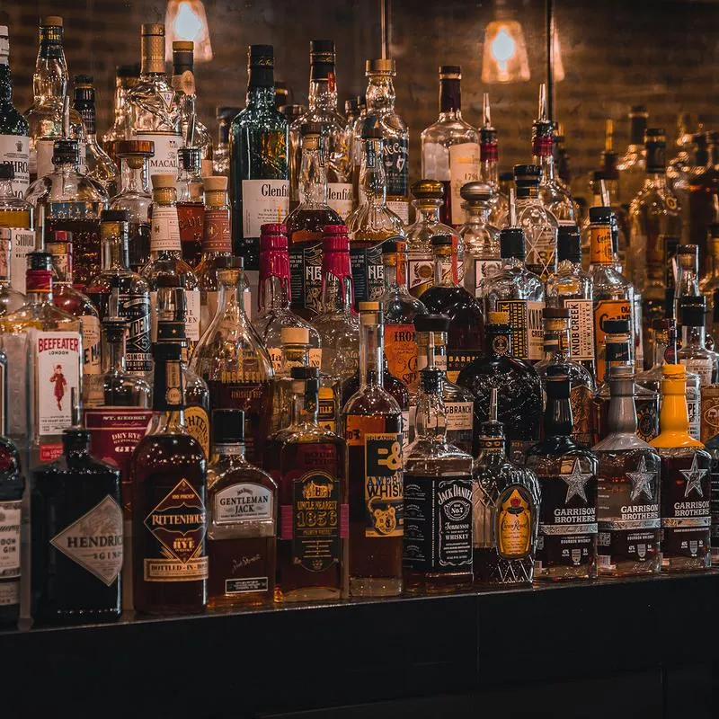 The back bar of a restaurant with a large variety of liquor bottles on tiered shelves.