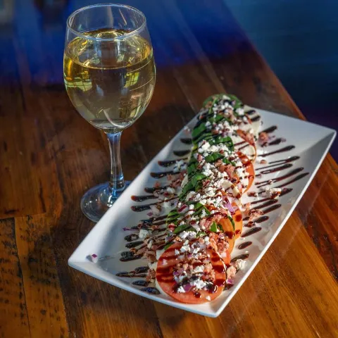 Caprese salad served with a glass of white wine.