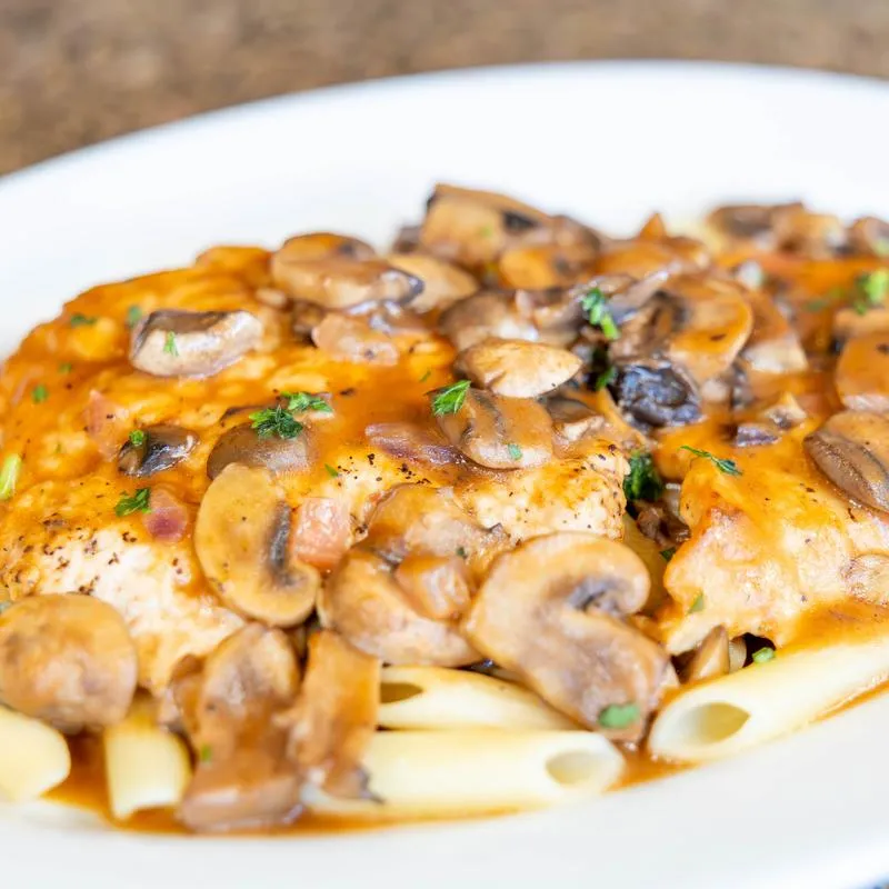 Chicken marsala with mushrooms served over pasta.