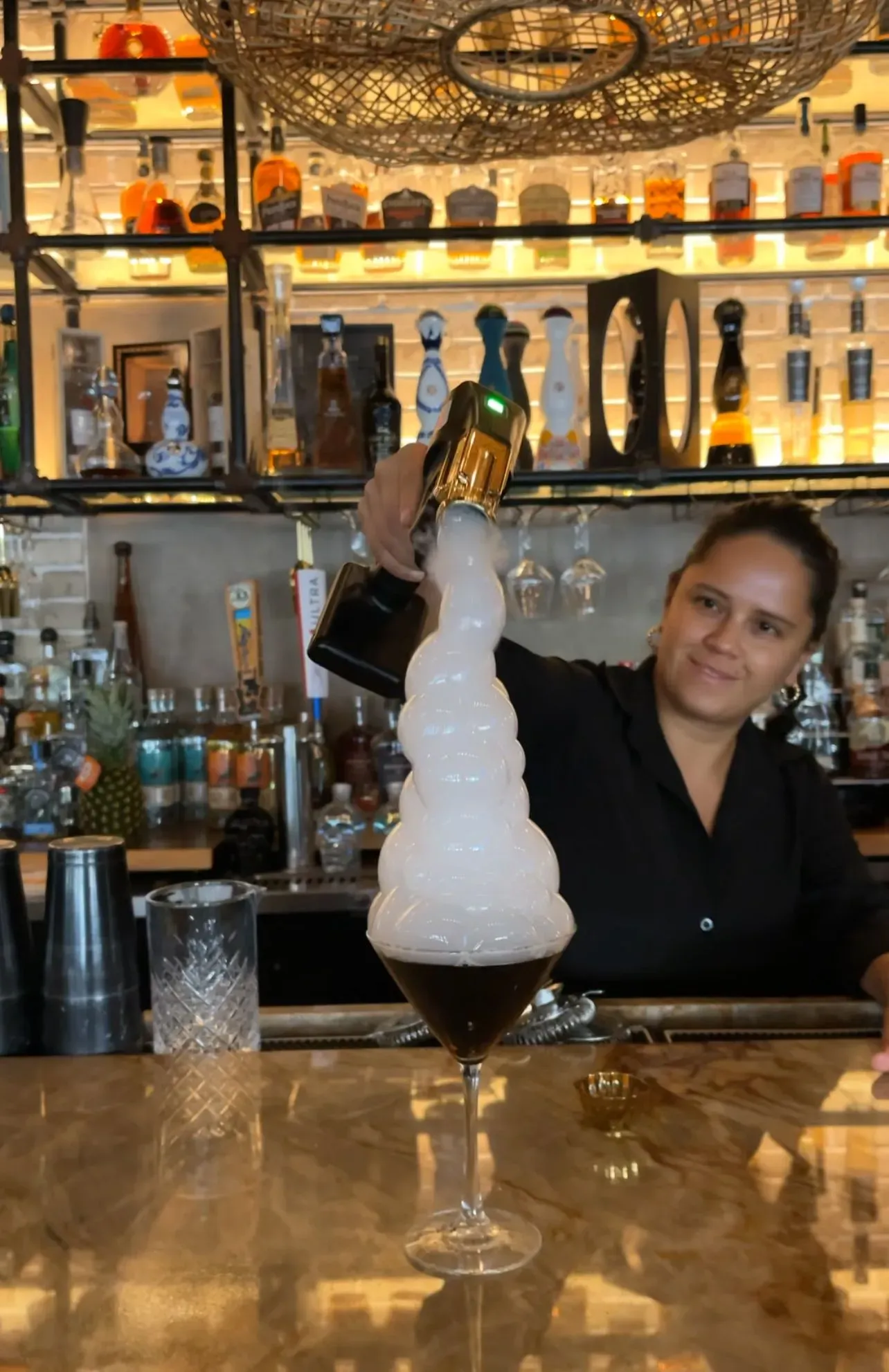 A woman is pouring champagne into a martini glass.
