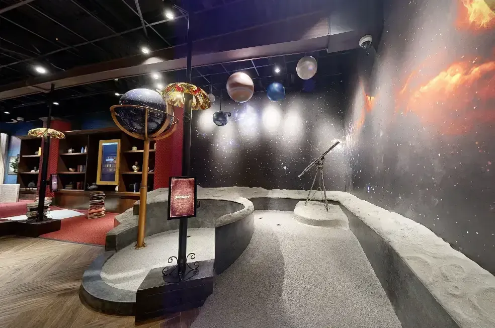 Space-themed hole on the Library Course at Puttery Miami with hanging planets, a telescope, star-filled walls, and an astronomy-inspired putting lane.