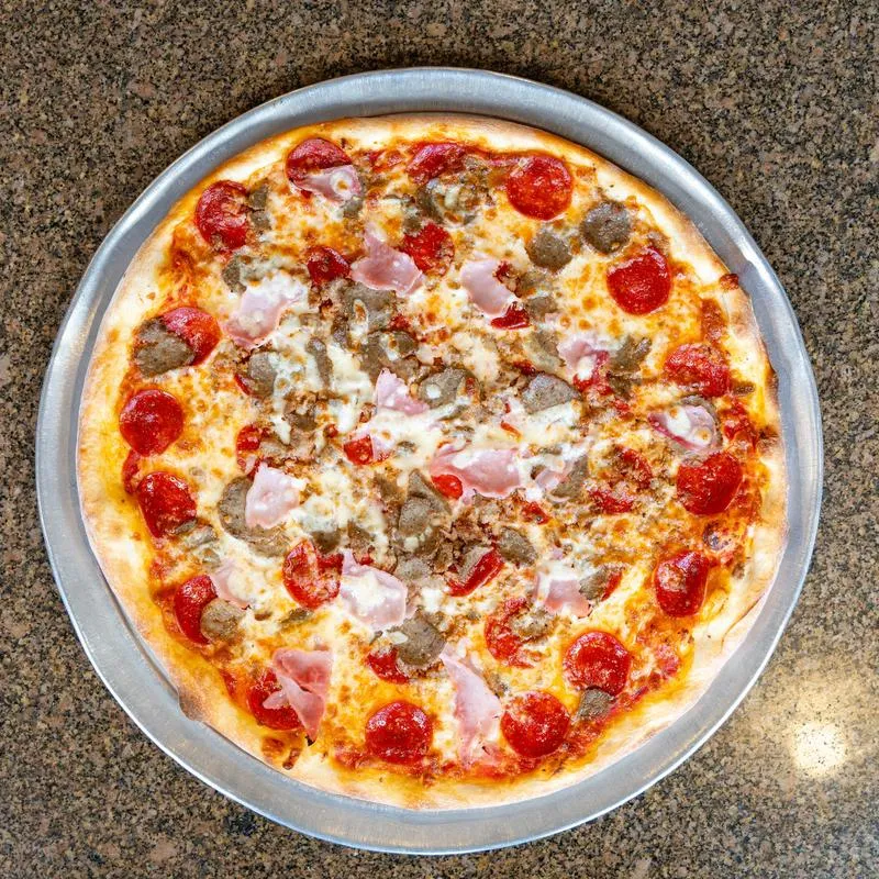Meat pizza with pepperoni and sausage on a metal tray.