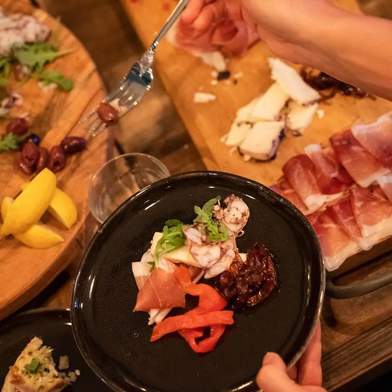 Hands serving various foods on wooden plates