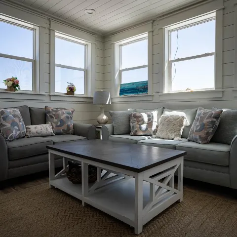 A cozy interior - two sofas, a coffee table and large windows letting in natural light.