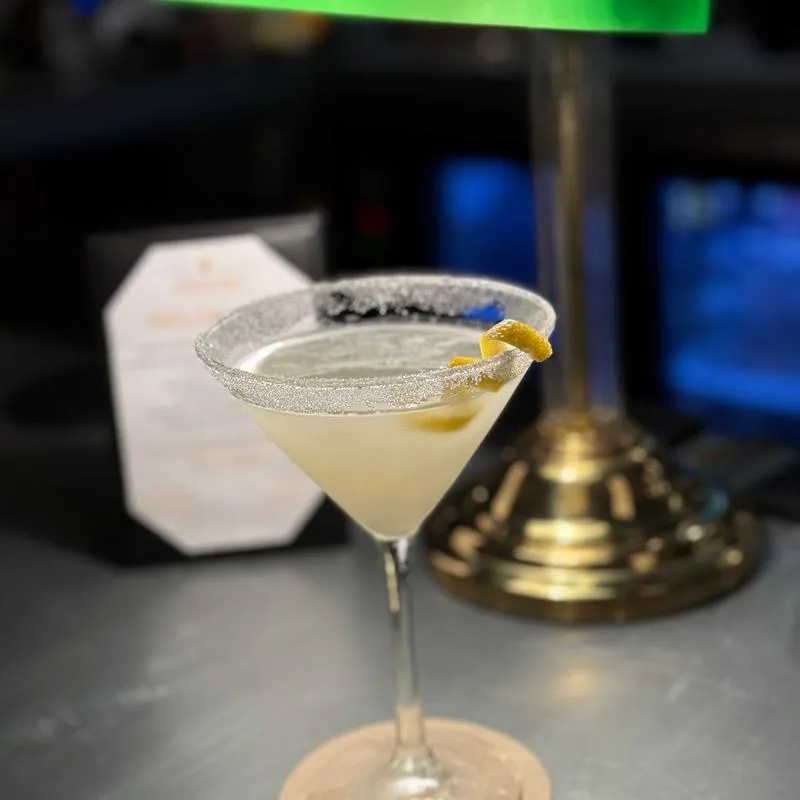 Cocktail served in a rimmed martini glass, garnished with a lemon peel.