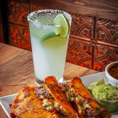 Birria tacos served alongside a Margarita cocktail.