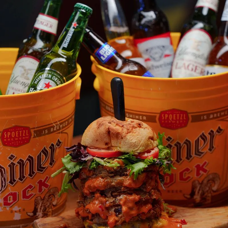 Tucker Duke Burger served alongside two ice buckets filled with various bottles of beer.