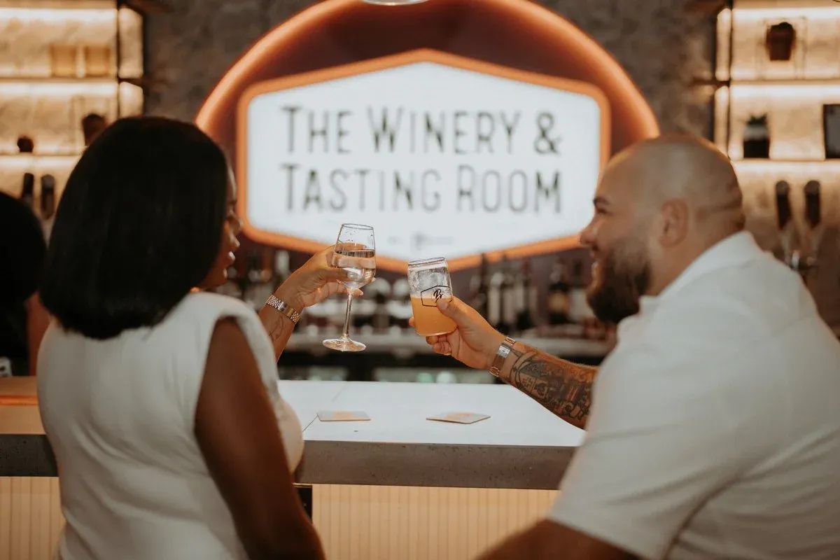 A man and woman toast with drinks in a winery tasting room