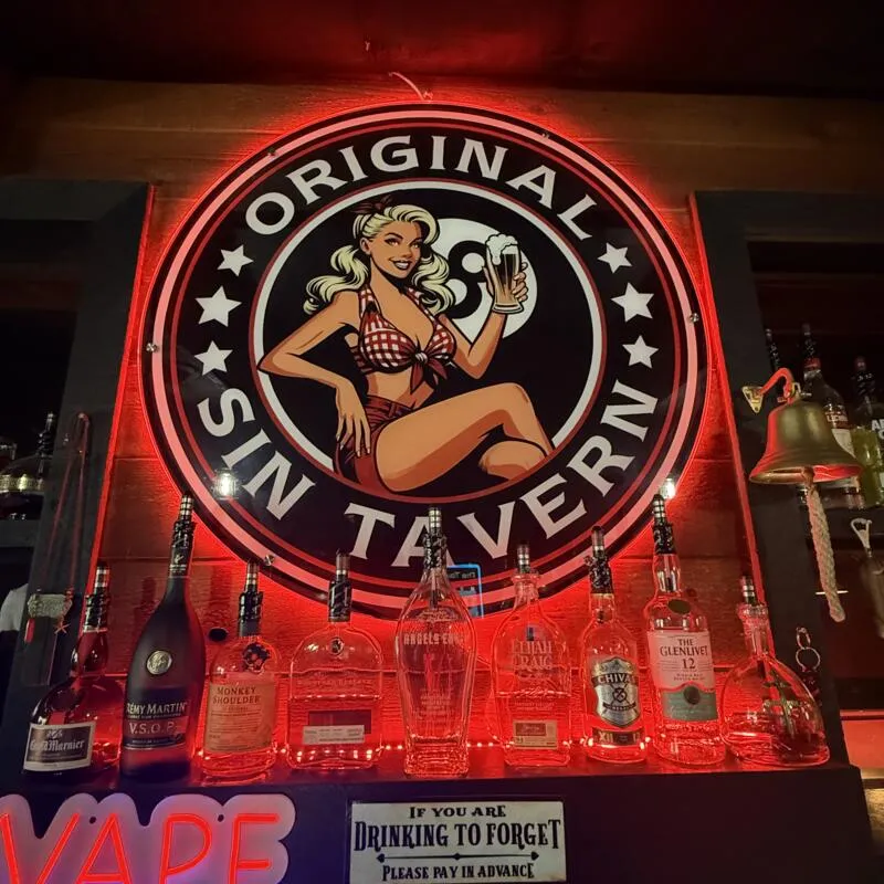 Bar display with illuminated tavern sign and bottles.