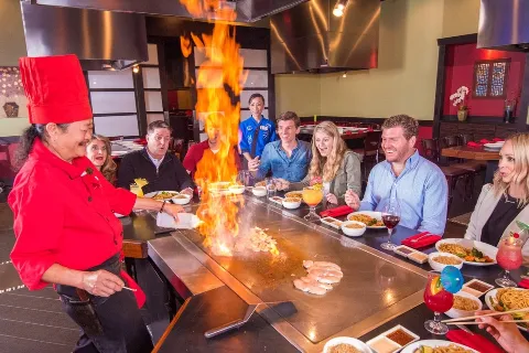 Guests sitting at Teppanyaki table with chef cooking at kobe