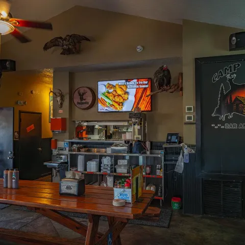 Rustic bar and grill interior with picnic tables and service counter.