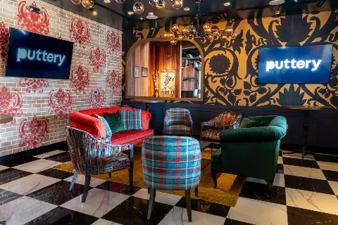 Lounge at Puttery Miami with plaid accent chairs, colorful sofa seating, checkerboard floors and bold patterned walls.