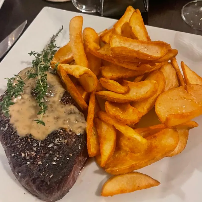 Steak Frites topped with green peppercorn sauce and hresh herbs.