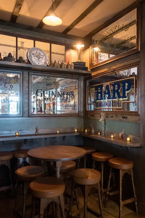 Round tables and stools beneath vintage Guinness and Harp mirrors at Delany's Public House.