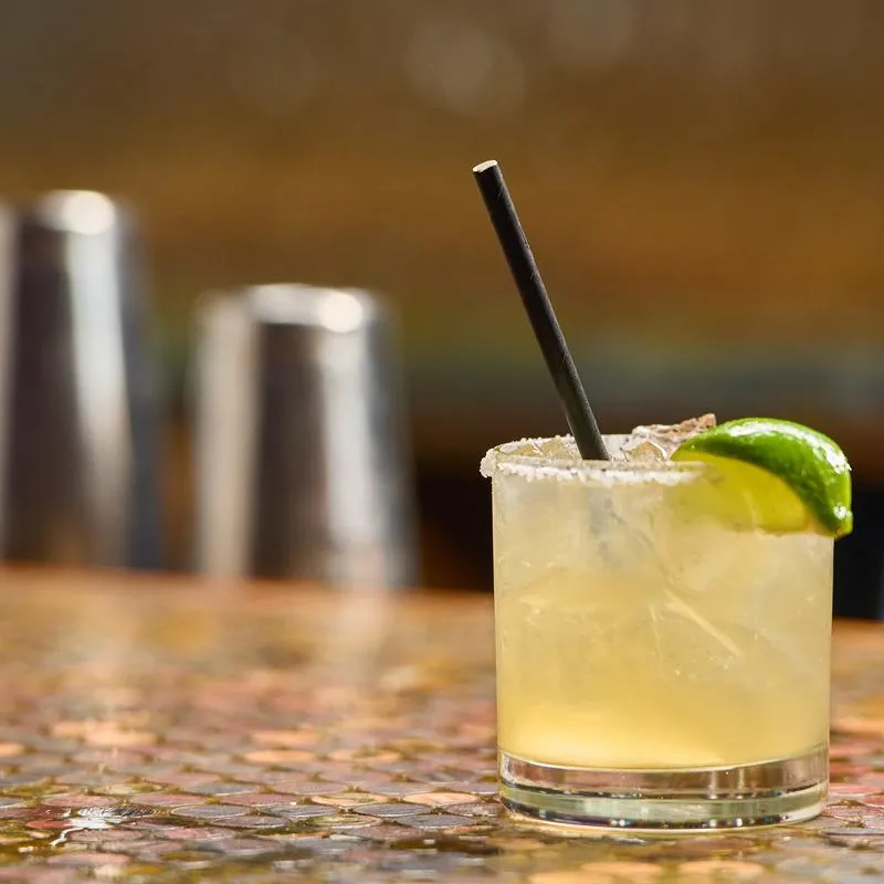 Margarita served in a salt-rimmed rocks glass with lime wedge garnish.