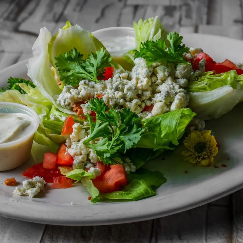 Wedge salad with blue cheese, tomatoes, parsley, and dipping sauce.