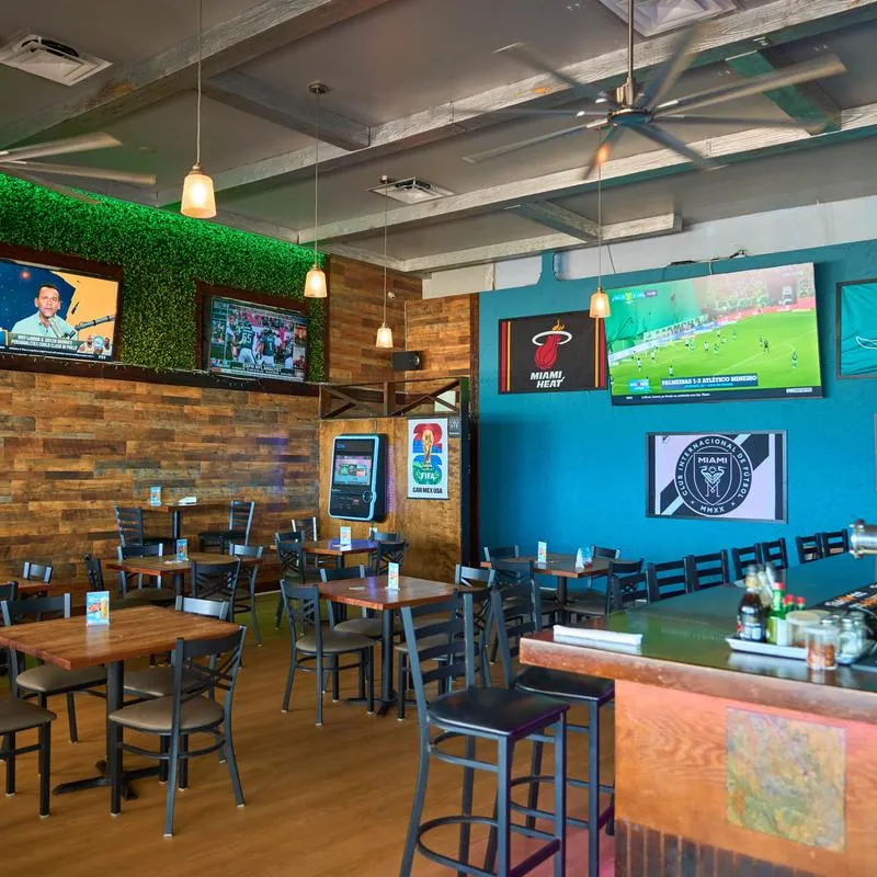 Casual sports bar featuring wooden tables, flat-screen TVs, and Miami sports decor.