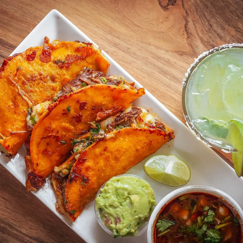 Birria Tacos served with guacamole, consomme and a lime wwedge.