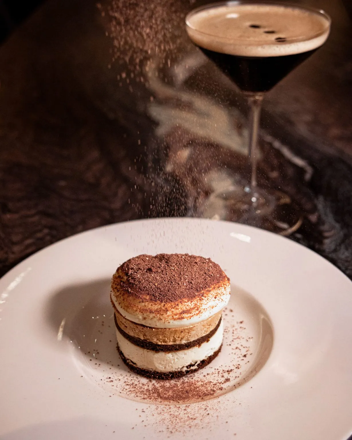 a chocolate layered dessert being dusted with cocoa powde