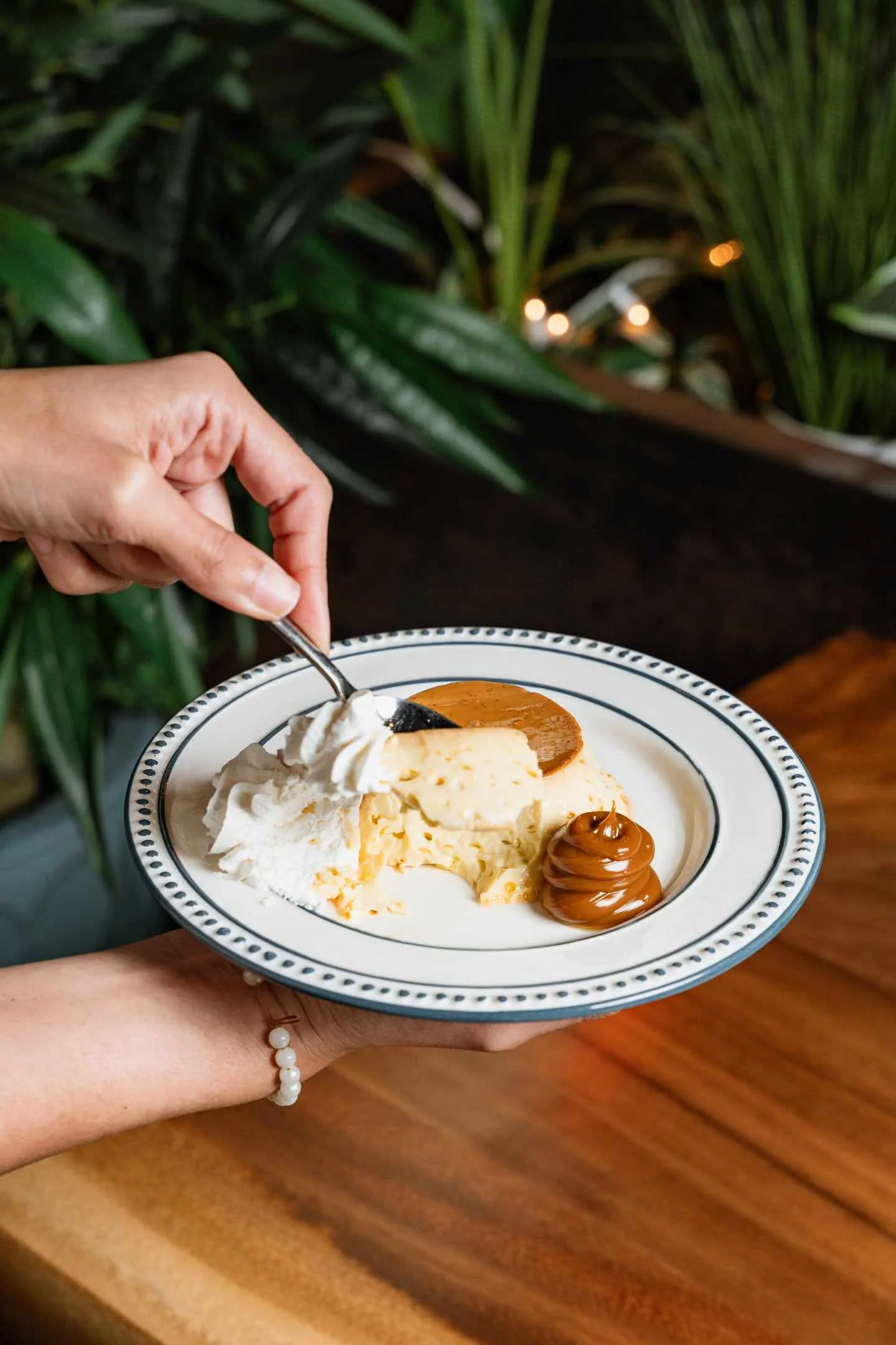 A flan with dulce de leche and whipped cream on a plate