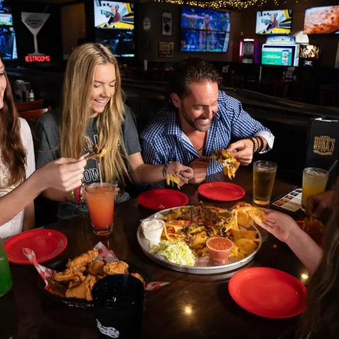 A group of people enjoying food and drinks at a table inside Duke's Brewhouse.