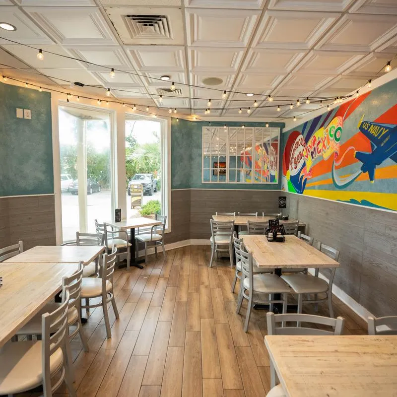 Interior featuring a colorful mural, tables, and string lights.