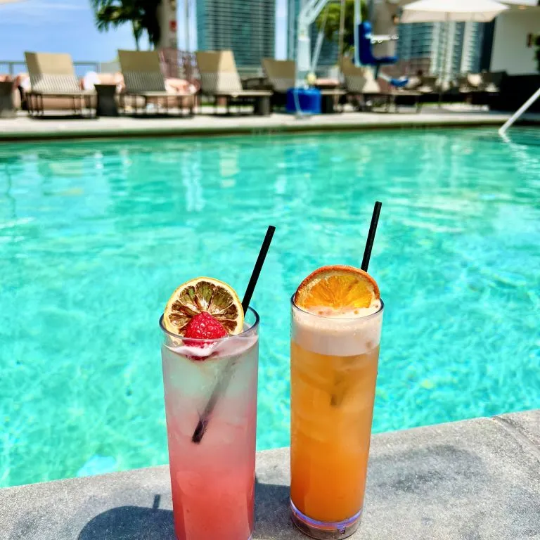 Two Drinks On A Table By A Pool