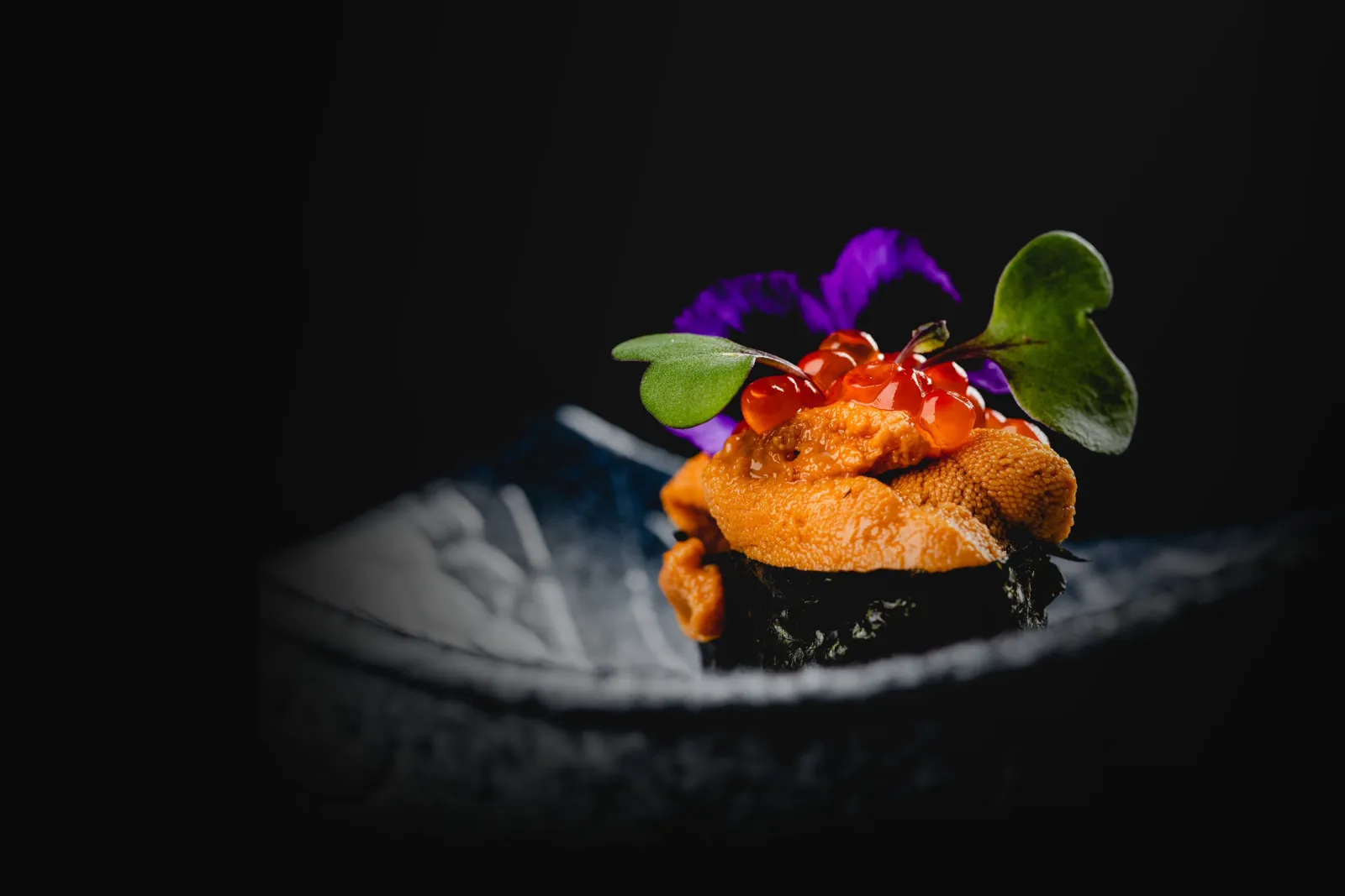 Fresh Uni and Ikura gunkan-maki sushi topped with orange sea urchin, red salmon roe