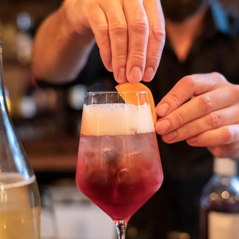Hands preparing a cocktail, glass, bottle