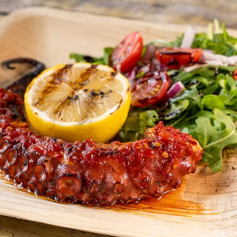 Charred Octopus with arugula salad and chili herb oil.