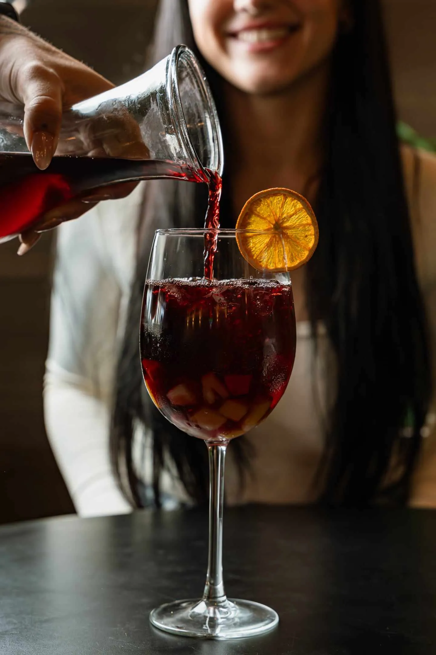 Sangria being poured into a glass with an orange slice