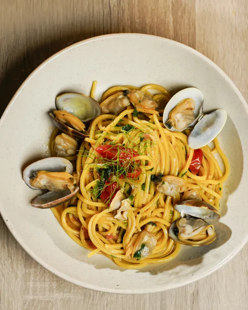 A bowl of pasta with clams and tomatoes.