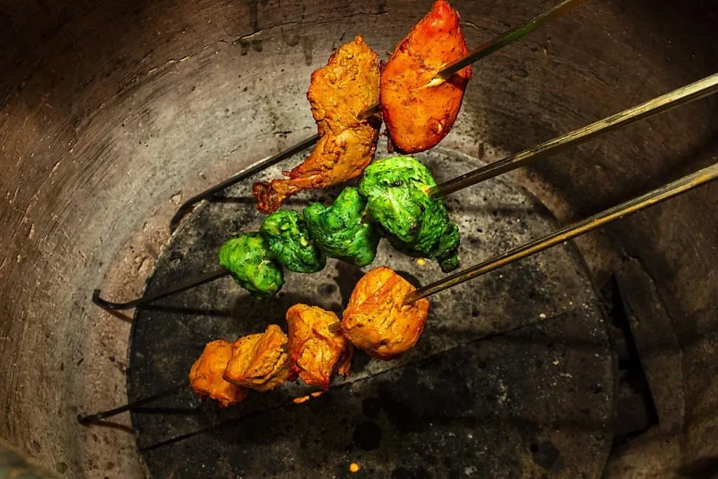 Skewers with colorful marinated meat in a tandoor oven.