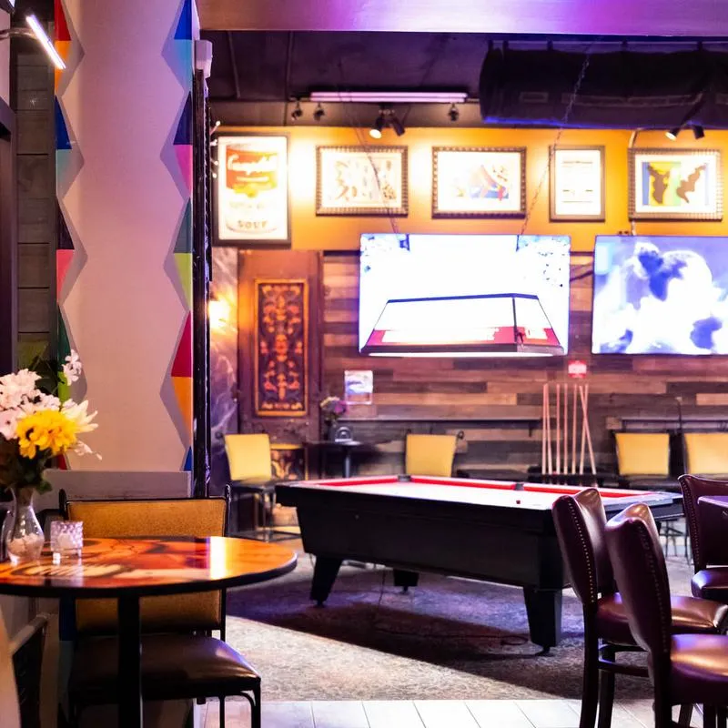 Interior, seating area with a pool table and wall TVs.