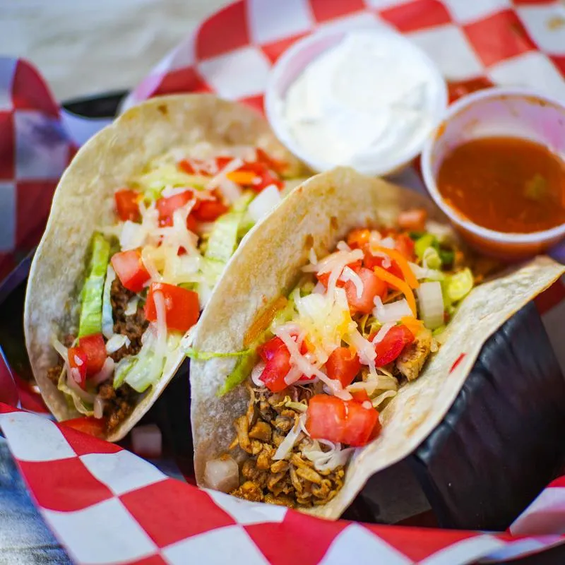 Two tacos served with salsa and sour cream.