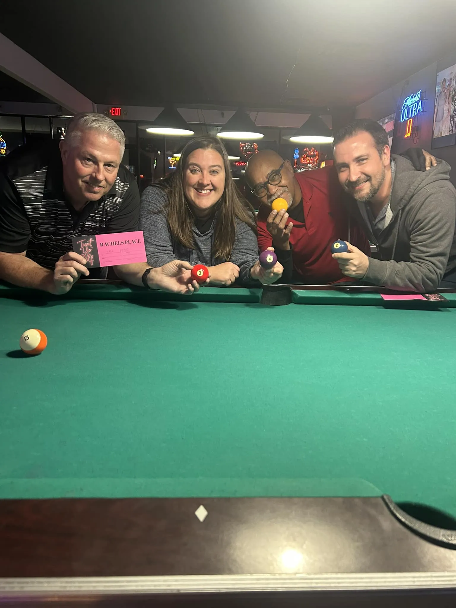 A group of cash-tournament winners holding cues at the pool table.