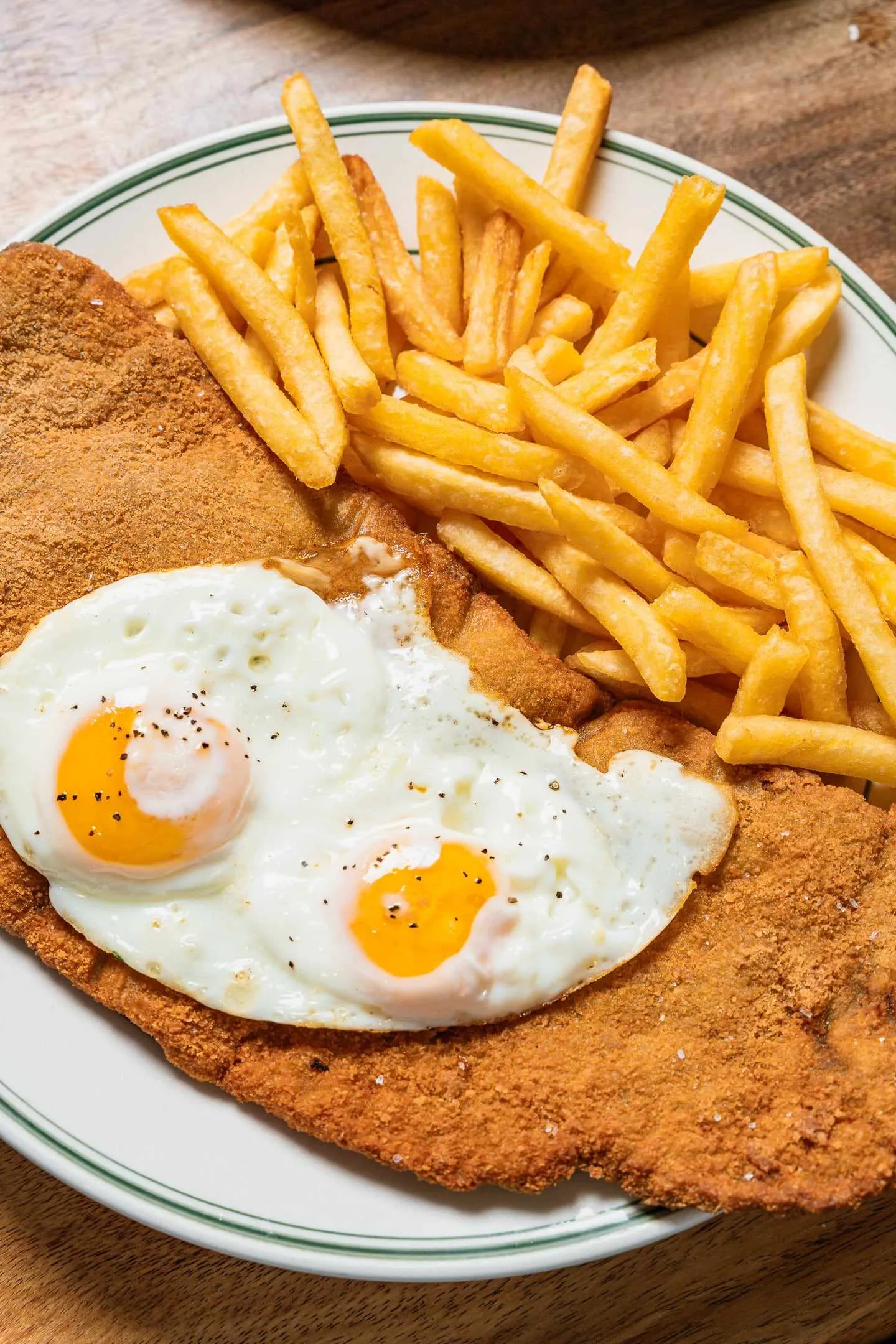 Milanesa a caballo: a breaded steak with two fried eggs and a pile of french fries
