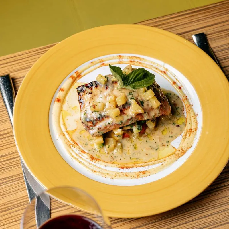 Baked white fish topped with vegetables, in a white wine sauce.